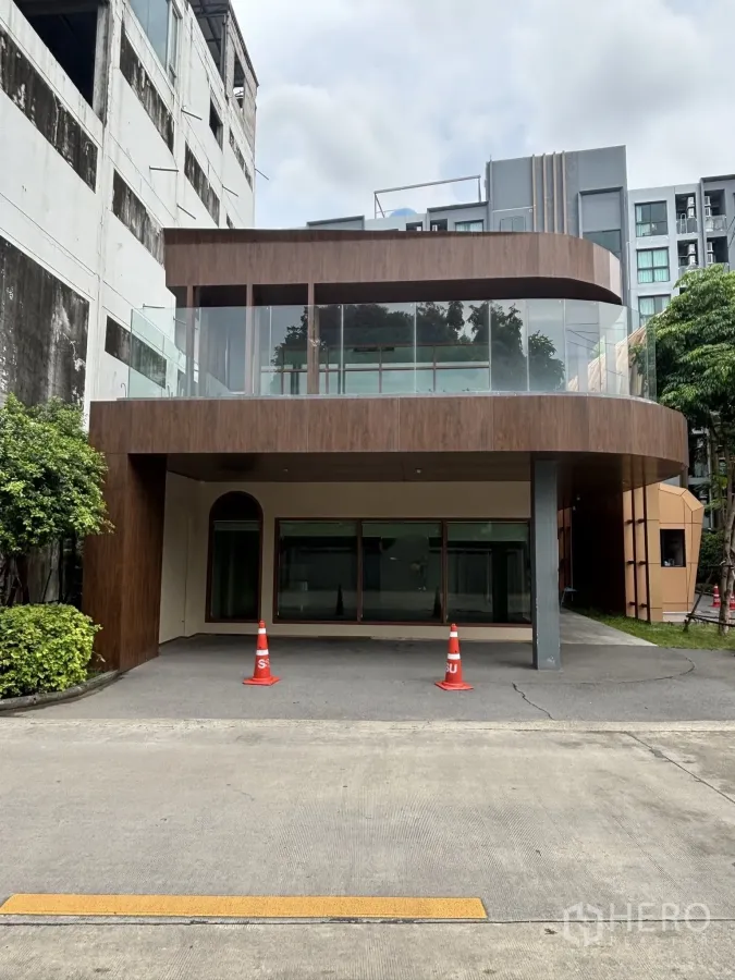 零售空间 for rent in Watthana, Bangkok - 现代两层零售建筑外观，弧形玻璃阳台与有顶门前区域。