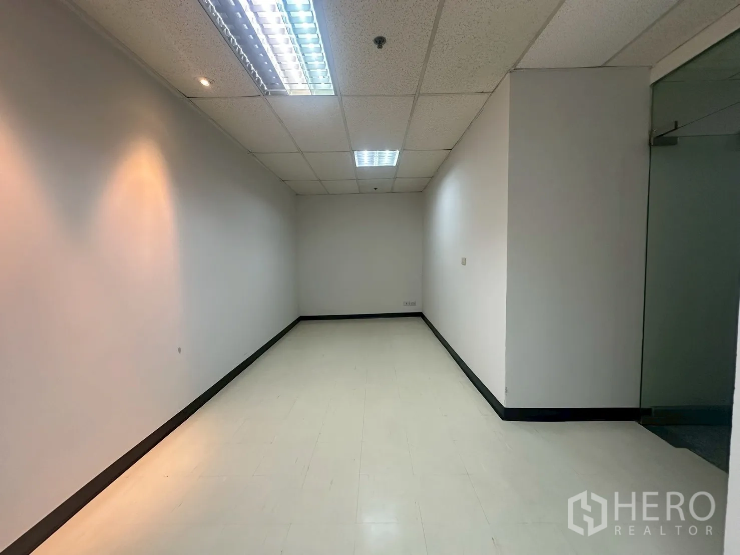 办公空间 出租 - 带墙面重点照明的多功能或接待区，旁有玻璃门。
