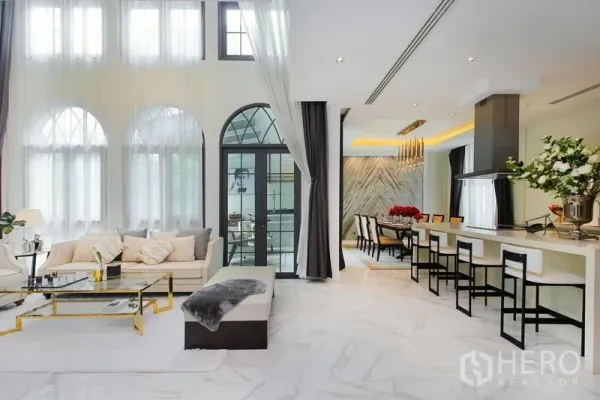 Detached House for rent or sale in Watthana, Bangkok - Open-plan lounge, dining and island kitchen under double-height arched windows.