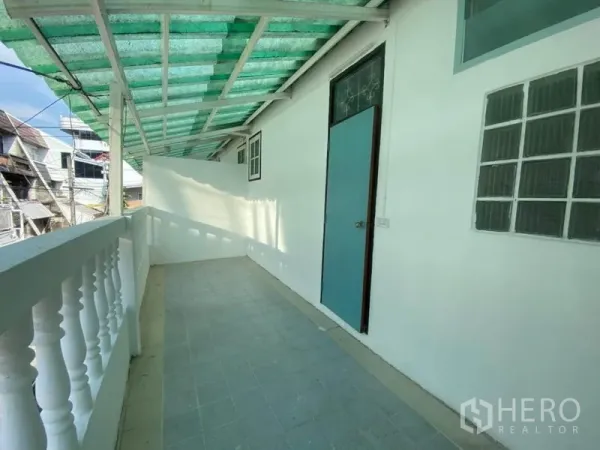 Townhouse for rent in Watthana, Bangkok - Long covered balcony with green awning, white balustrade and side door.
