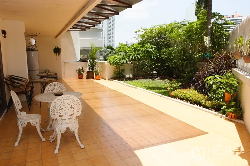 Condominium for rent in Khlong Toei, Bangkok - Large tiled terrace with outdoor seating and a private garden overlooking nearby high‑rises.