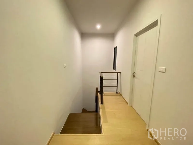 Townhouse for rent in Prawet, Bangkok - Upper corridor with wood steps, handrail and ceiling spotlight.