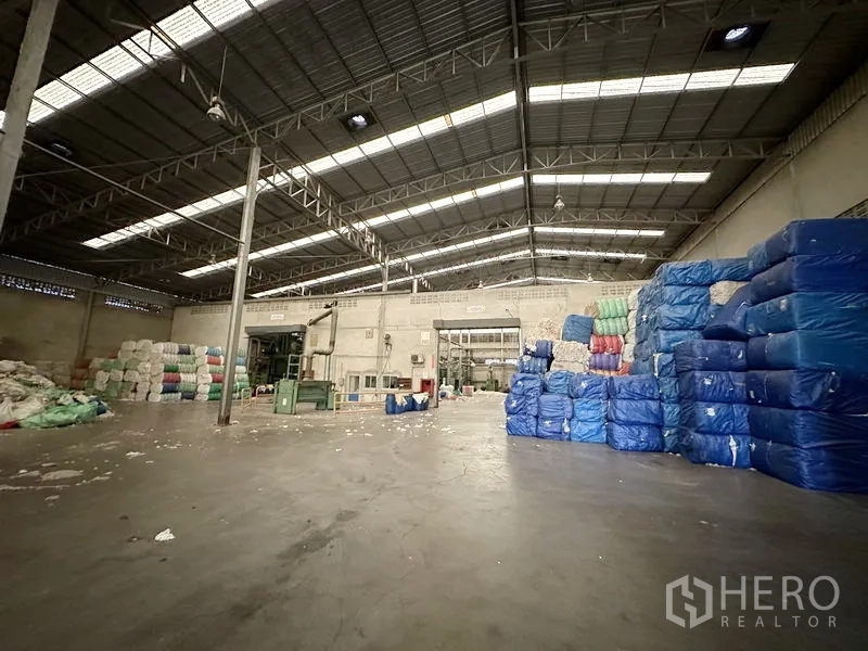 Factory for rent in Bang Bua Thong, Nonthaburi - Production and storage zone with steel truss roof and stacks of wrapped bales.