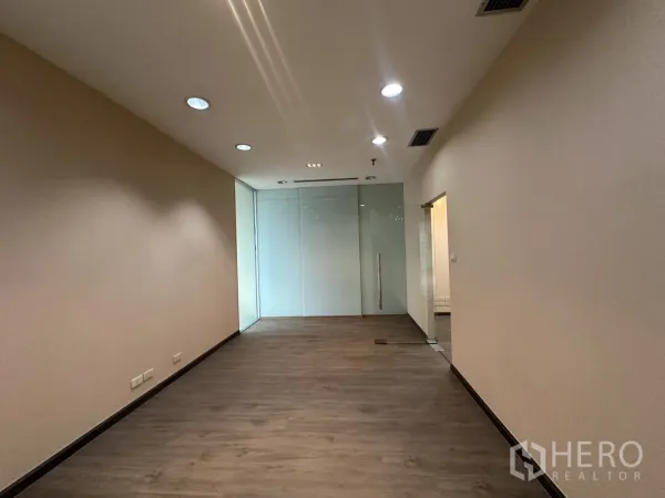 Office Space for rent in Bang Rak, Bangkok - Long workspace with a glass partition wall and ceiling spotlights.