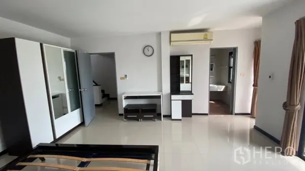 Townhouse for rent in Bang Na, Bangkok - Spacious bedroom with wardrobes, air conditioner, desk and access to an ensuite.