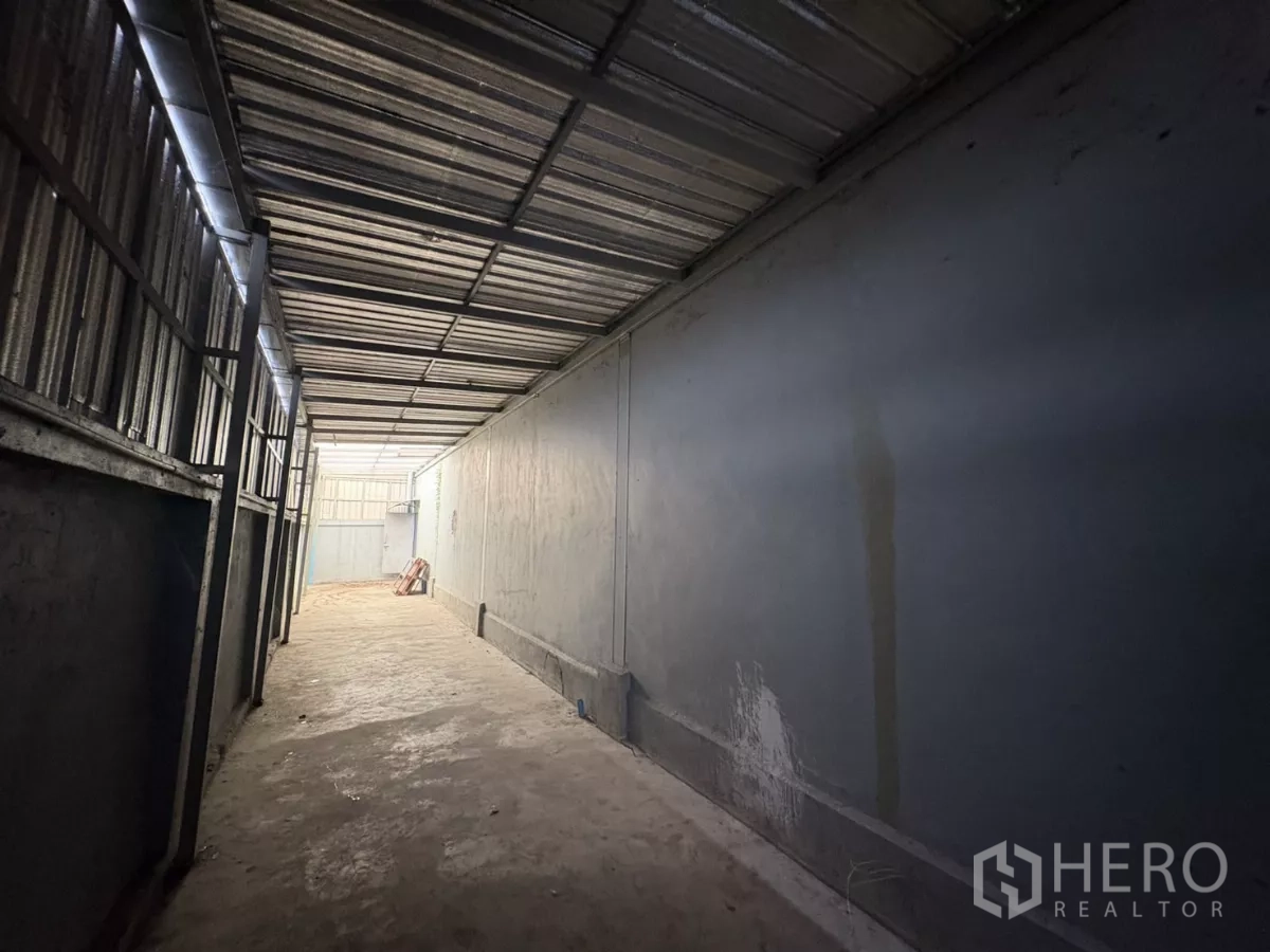 Warehouse for rent in Bang Phli, Samut Prakan - Narrow covered service corridor with steel cladding and concrete surface.