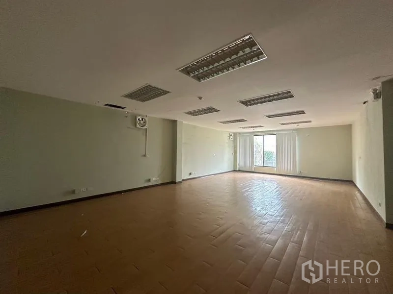 Warehouse for rent in Prawet, Bangkok - Open office room with ceiling lights and a windowed exit at the far end.