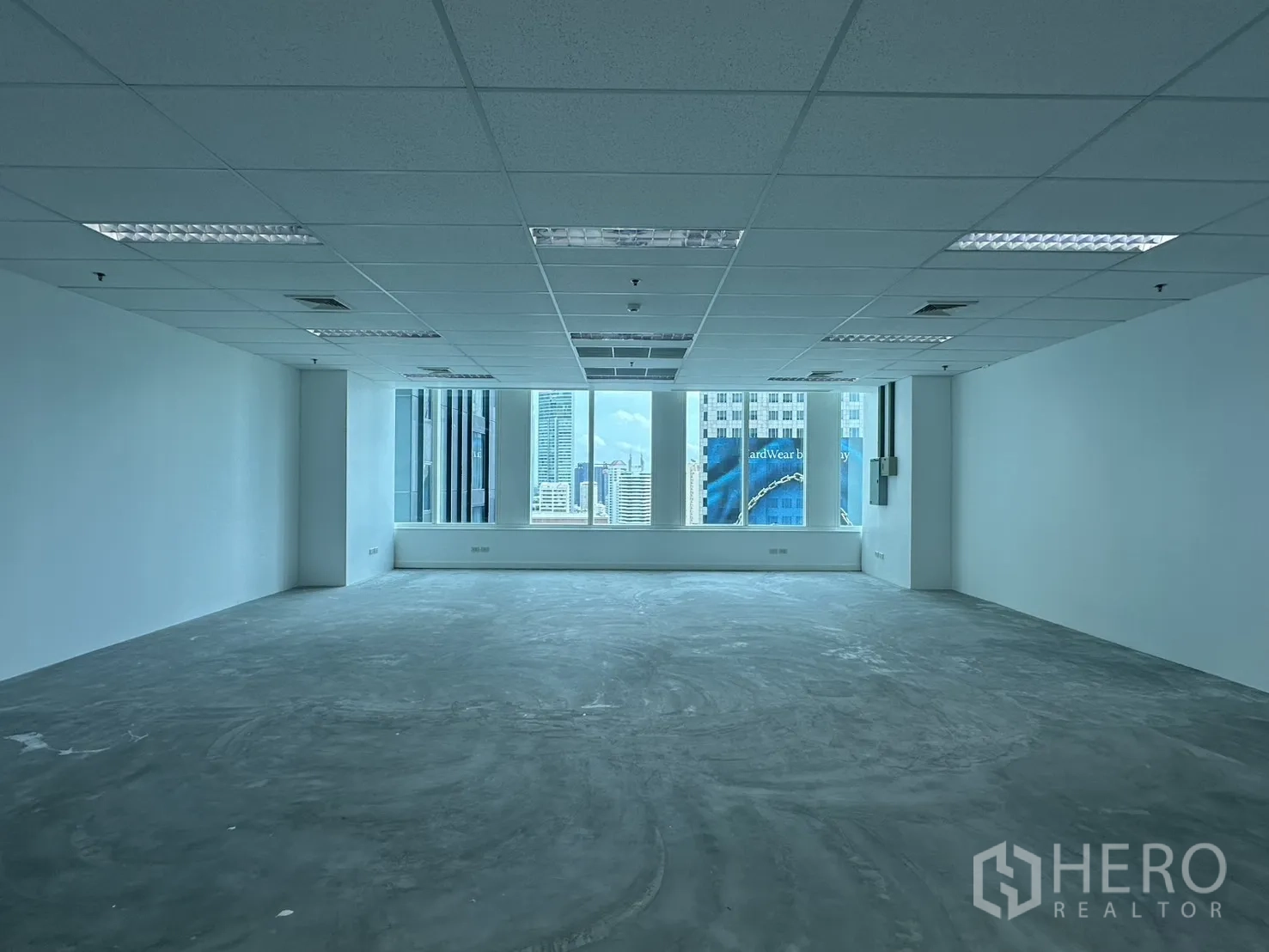 办公室 for rent in Watthana, Bangkok - 从室内正面望向窗外的办公室视角，天际线景观与网格吊顶。