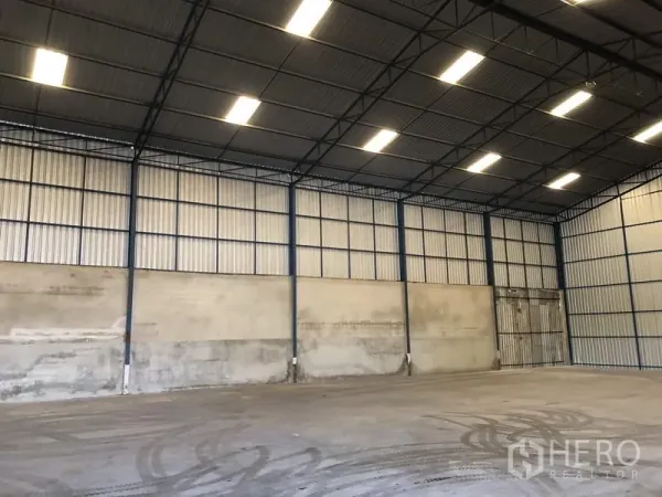 Warehouse for rent in Pathum Thani - Wide clear-span warehouse with metal cladding walls, large sliding doors and evenly lit roof panels.