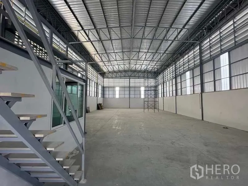 Warehouse for rent in Bang Bua Thong, Nonthaburi - Open-plan warehouse interior with high steel truss ceiling and concrete flooring.