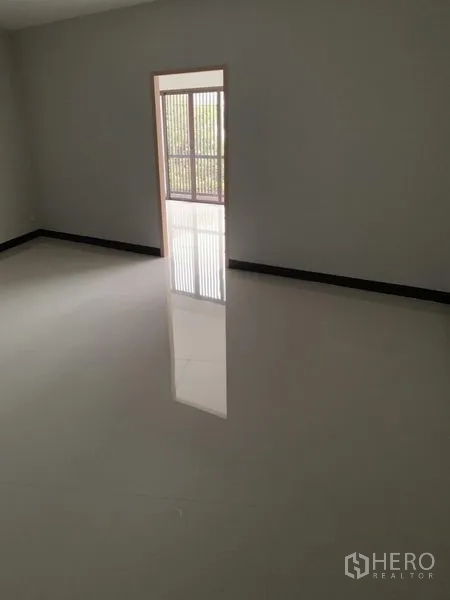 Shophouse for rent in Suan Luang, Bangkok - Empty upper-floor room with glossy white tiles and a doorway to a balcony with vertical slats.
