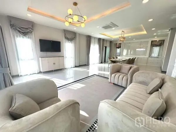 Detached House for rent in Bang Phli, Samut Prakan - Bright open‑plan living and dining room with beige sofas, chandeliers and full‑height curtains