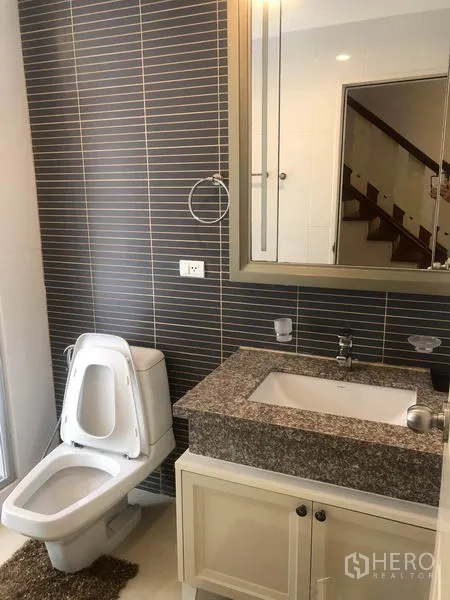 Detached House for rent or sale in Pak Kret, Nonthaburi - Bathroom with granite-top vanity, mirror cabinet and striped tile wall.