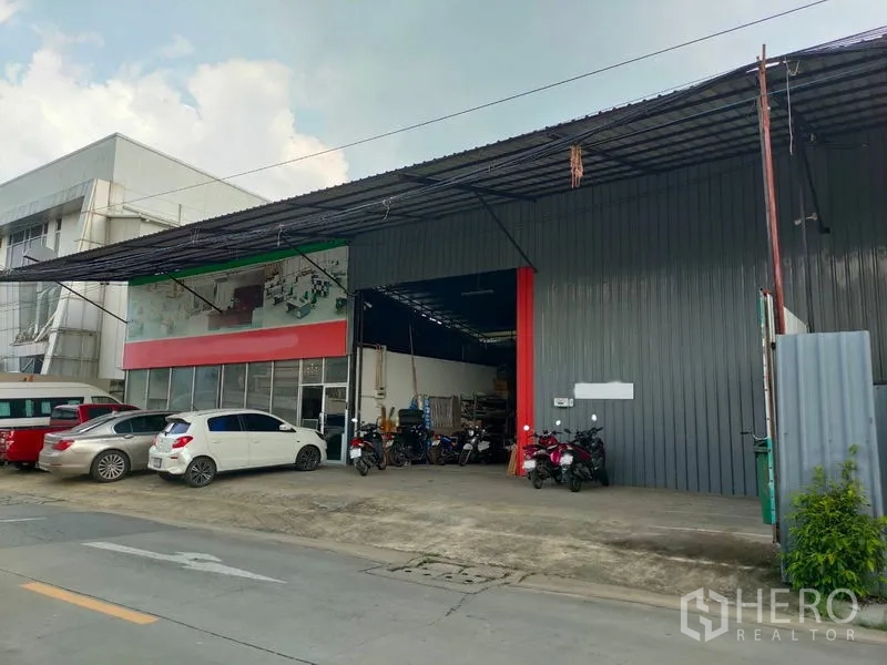 Warehouse for rent in Bang Kapi, Bangkok - Street-facing warehouse with wide roller entry, metal facade, covered loading bay, and on-site parking in Bang Kapi.