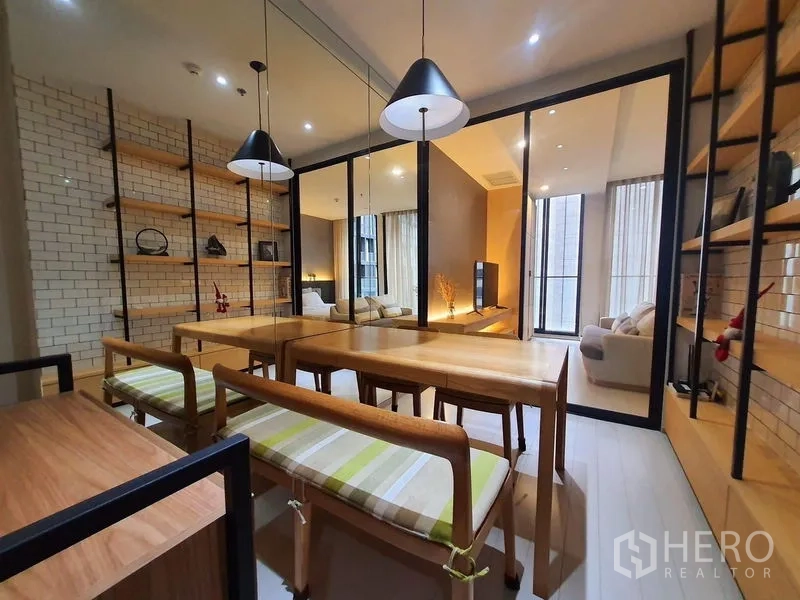 Condominium for rent in Pathum Wan, Bangkok - Dining room with wooden table and benches, pendant lighting, mirrored wall and open shelves.