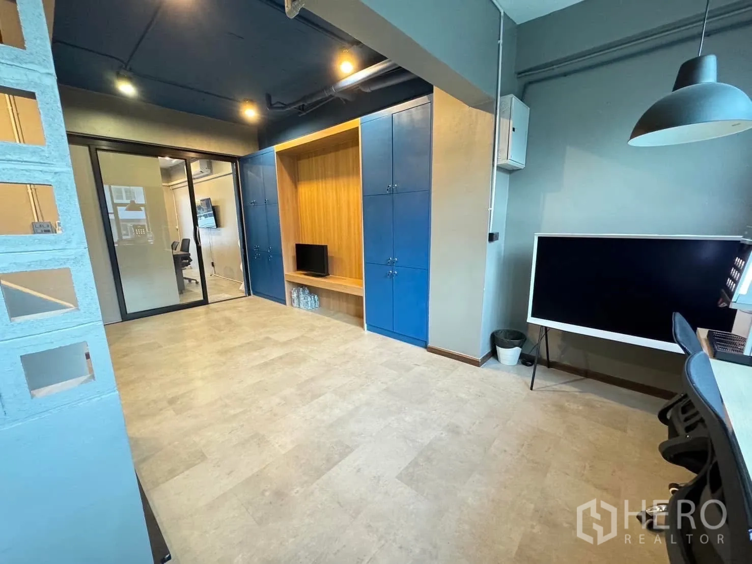 Home Office for rent in Watthana, Bangkok - Open work area with built-in blue storage cabinets and a glass sliding door.