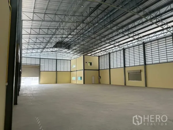 Warehouse for rent or sale in Bang Phli, Samut Prakan - High-clearance warehouse bay with mezzanine office cube, skylights and smooth concrete slab.