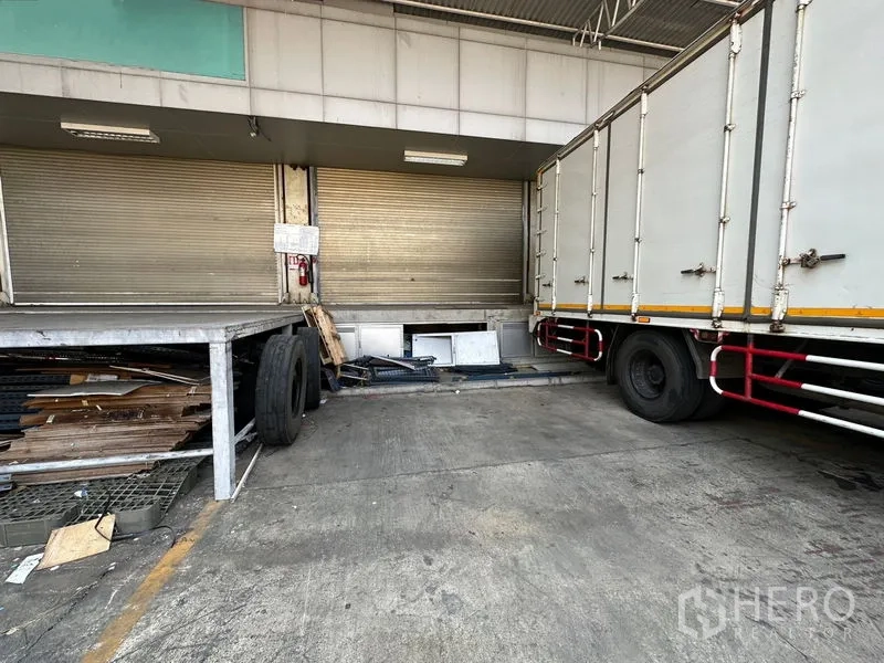 Warehouse for rent in Lam Luk Ka, Pathum Thani - Loading dock platform with roller doors next to a box truck under a metal canopy.