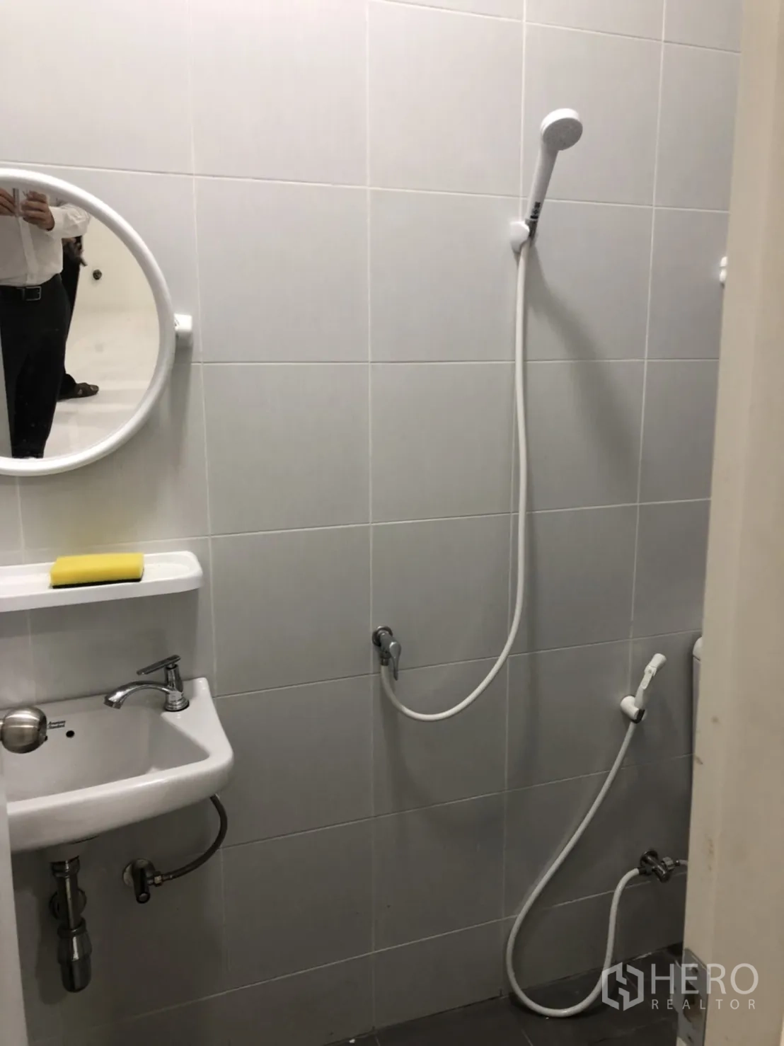 Warehouse for rent in Lam Luk Ka, Pathum Thani - Tiled bathroom with wall-mounted sink, round mirror and handheld shower set.
