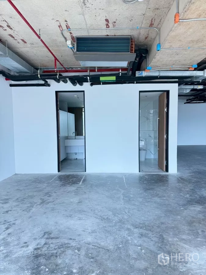 Office Space for rent in Din Daeng, Bangkok - In-suite restrooms behind a white partition wall under an exposed MEP ceiling in a shell-condition office.