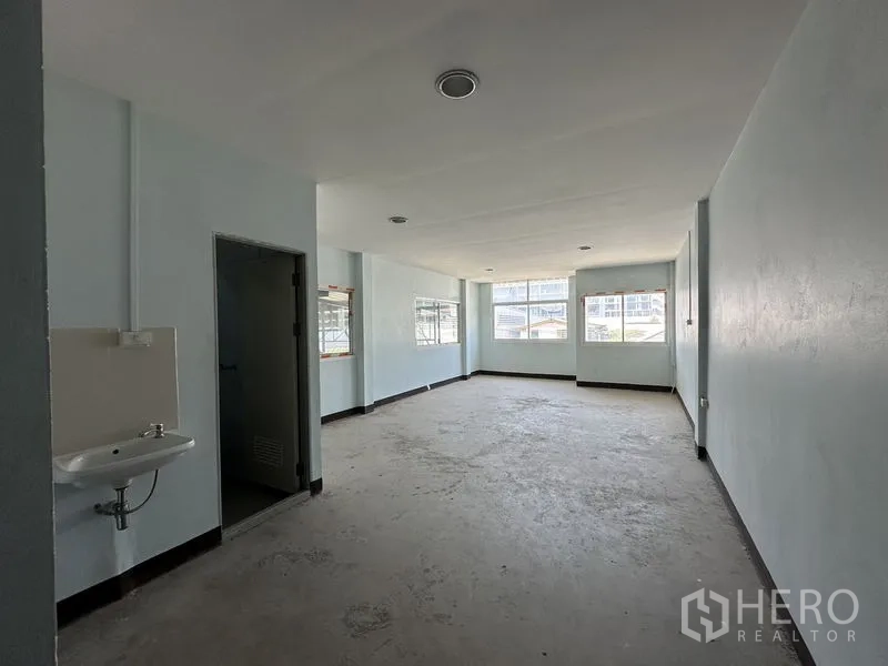 Warehouse for rent in Bueng Kum, Bangkok - Rear service corridor with metal cladding, utility sink and access door.