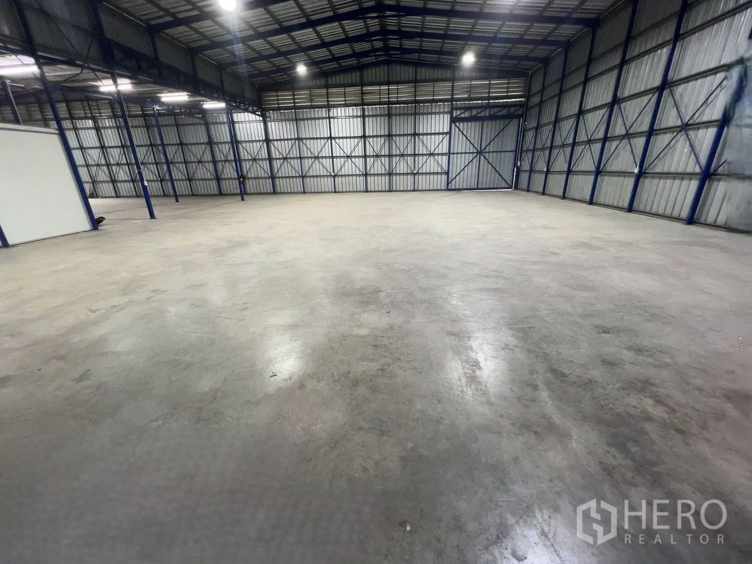 Warehouse for rent in Khlong Luang, Pathum Thani - Open storage area of the warehouse showing steel columns, metal cladding walls, and a smooth concrete surface.