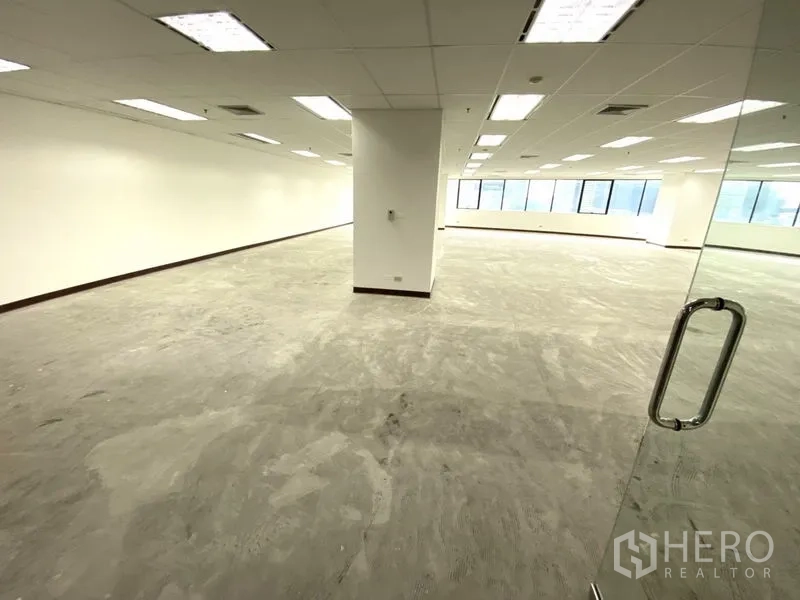Office Space for rent - Open-plan 145 sqm office with glass entry, white walls, drop ceiling lights and large windows.