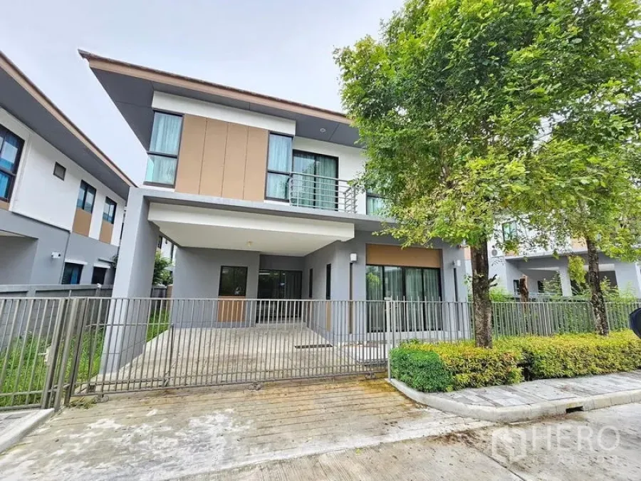 Detached House for rent in Prawet, Bangkok - Front exterior of the detached house with fenced carport and landscaped verge.