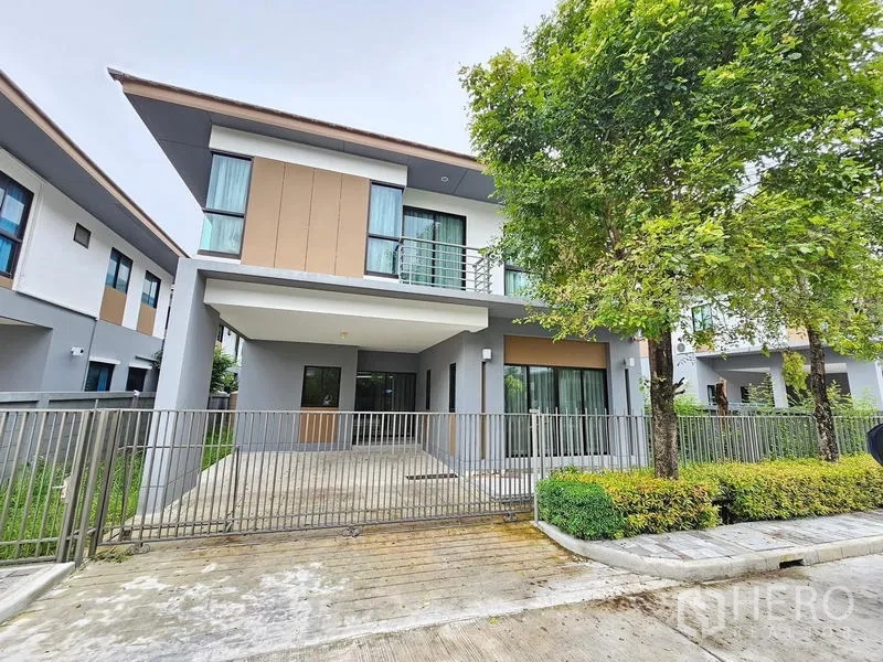 Detached House for rent in Prawet, Bangkok - Front exterior of the detached house with fenced carport and landscaped verge.