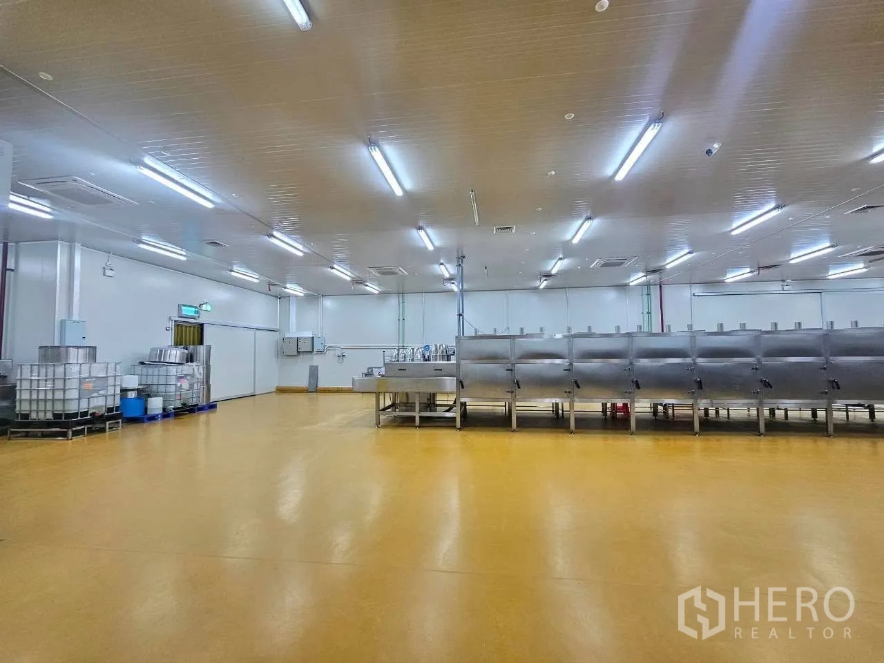 Factory for rent in Mueang Samut Sakhon, Samut Sakhon - Expansive processing hall with machinery and bright LED lighting.