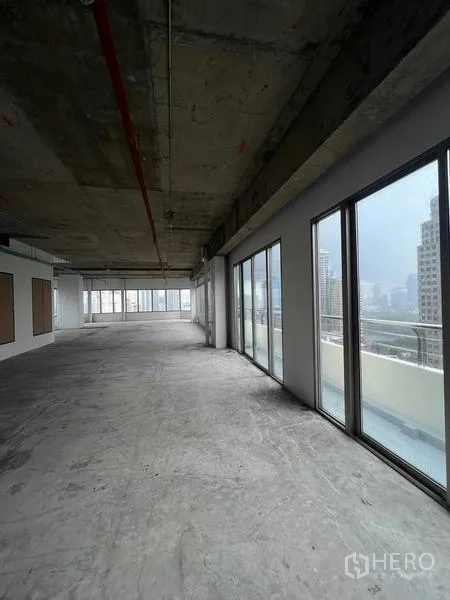 Office Space for rent in Watthana, Bangkok - Open office shell with floor-to-ceiling glass and balcony rail, looking out to city towers.