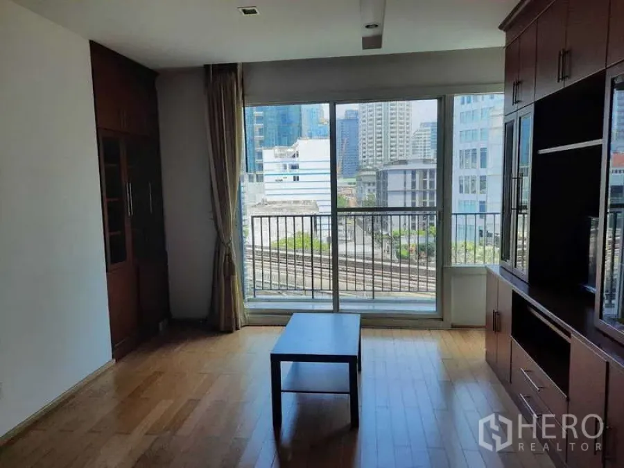 Condominium for rent in Khlong Toei, Bangkok - Living room with sliding glass doors opening to a balcony and skyline view.