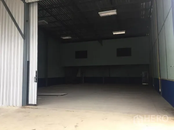 Warehouse for rent in Lat Krabang, Bangkok - Wide entrance to warehouse with partially open metal door and ample loading space.