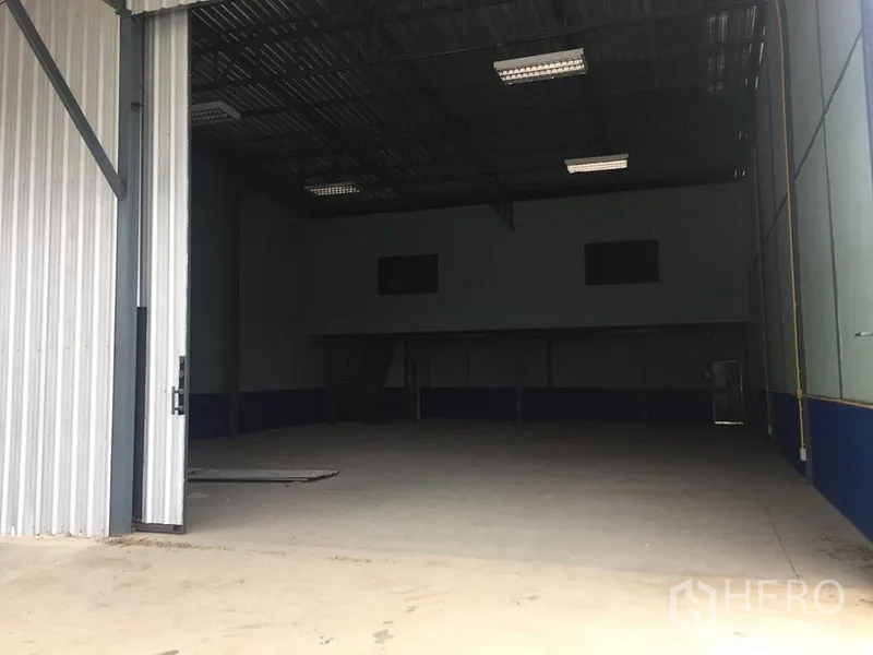Warehouse for rent in Lat Krabang, Bangkok - Wide entrance to warehouse with partially open metal door and ample loading space.
