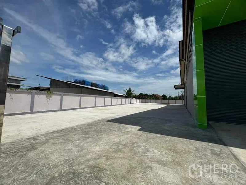 Factory for sale in Samut Sakhon - Large paved forecourt along the factory side for truck access and maneuvering.