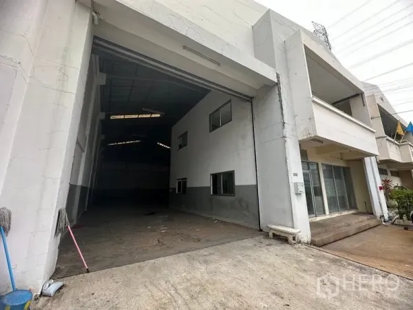 Factory for rent in Khlong Luang, Pathum Thani - Factory façade with wide roller shutter entrance and attached office block.
