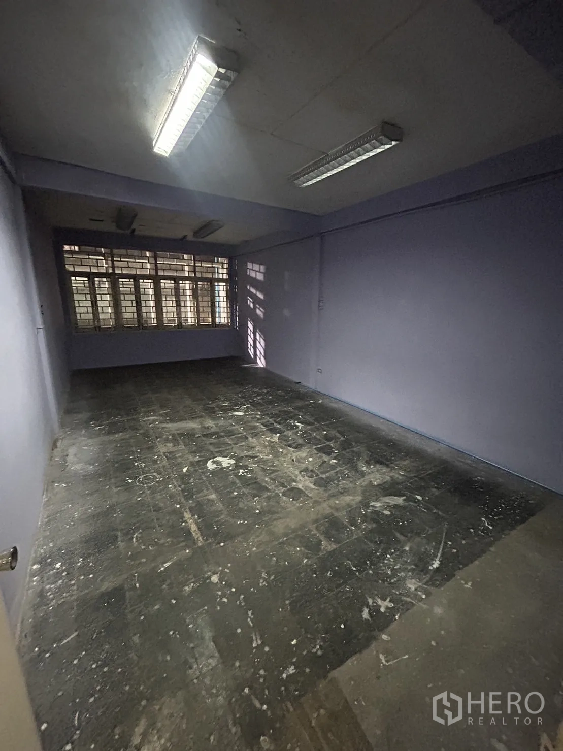 Shophouse for rent in Khlong Toei, Bangkok - Unfinished room with purple walls, fluorescent lighting, and worn concrete floor.