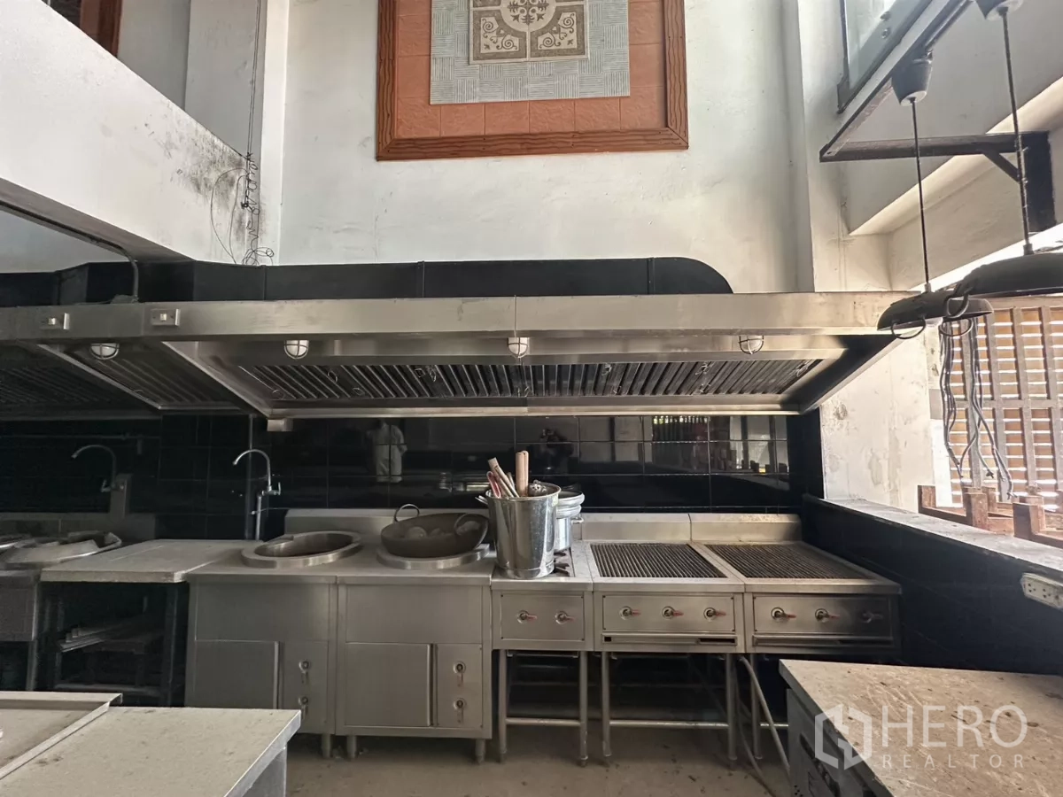 Shophouse for rent in Bang Na, Bangkok - Close view of stainless wok ranges, grills and a large exhaust hood in the fitted kitchen.