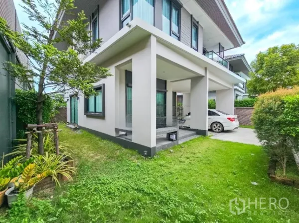 Detached House for sale in Lam Luk Ka, Pathum Thani - Side garden with lawn and covered porch beside the driveway of the detached house.