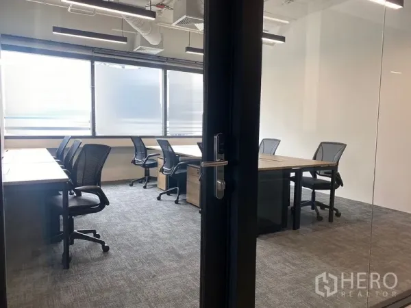 Office Space for rent in Bang Rak, Bangkok - View through a glass door into a bright office with multiple desks and frosted windows.