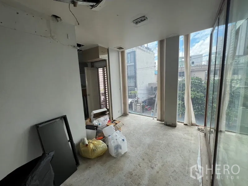 Retail Space for rent in Bang Rak, Bangkok - Upper-floor interior with floor-to-ceiling windows and unfinished floors overlooking the neighborhood.