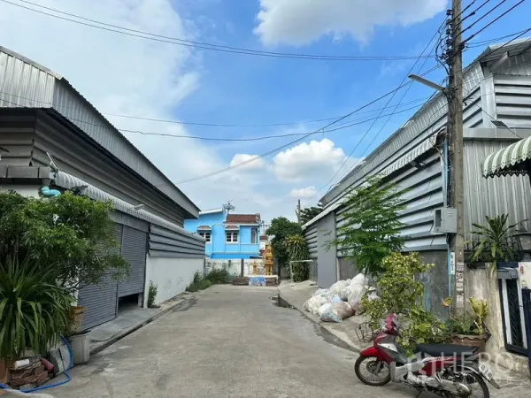 Warehouse for rent in Bueng Kum, Bangkok - Private lane between metal-clad warehouses in Bueng Kum under a blue sky.