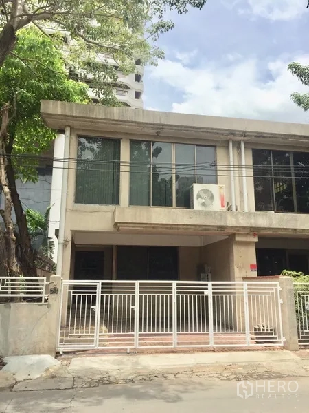 Townhouse for rent in Watthana, Bangkok - Front facade of gated townhouse with large upstairs windows and driveway.