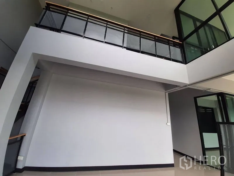 Factory for rent or sale in Lam Luk Ka, Pathum Thani - Interior mezzanine area with high ceiling and black metal railing.