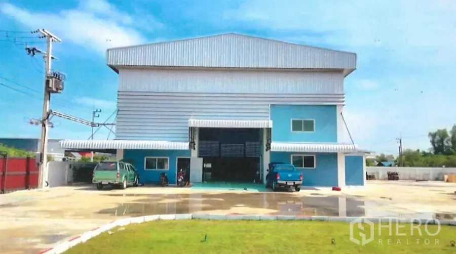 工厂 出售在Lat Lum Kaeo, Pathum Thani - 工厂正立面，蓝灰色金属外墙，宽大卷闸门与停车场