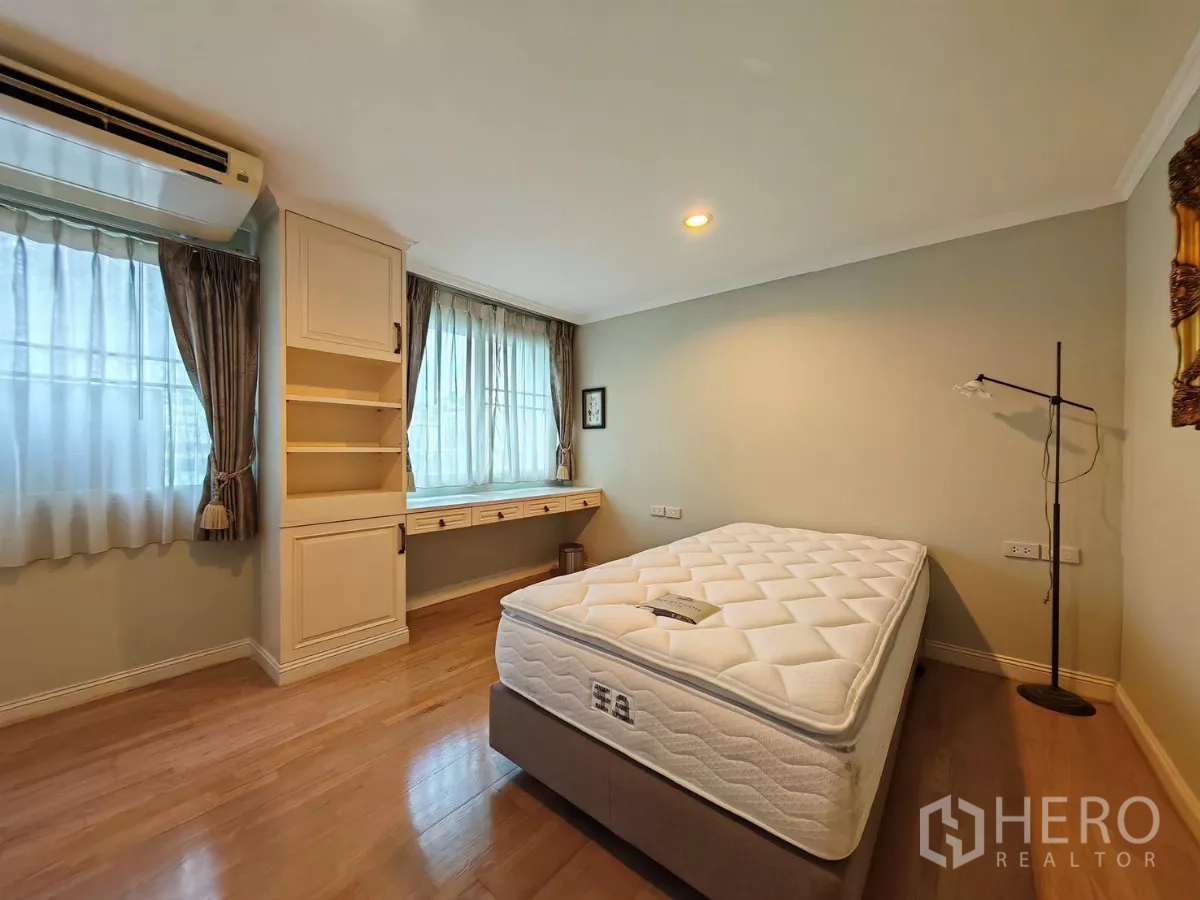 Condominium for rent in Pathum Wan, Bangkok - Bright bedroom with two windows, built-in desk and shelving, and a bed.