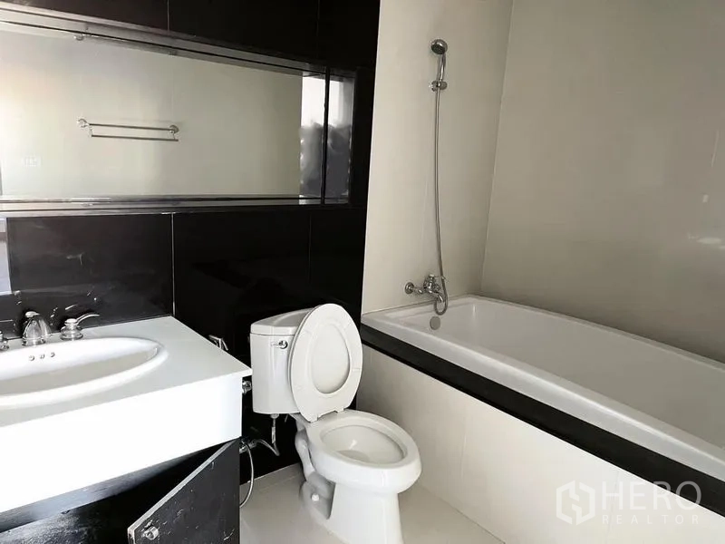 Condominium for rent in Pathum Wan, Bangkok - Bathroom with full-size bathtub, handheld shower and wide mirror.