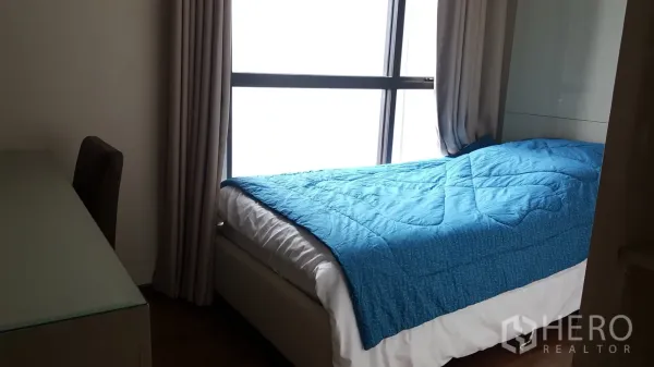 Condominium for rent or sale in Khlong Toei, Bangkok - Second bedroom with single bed, blue comforter, full-height window and a work desk.