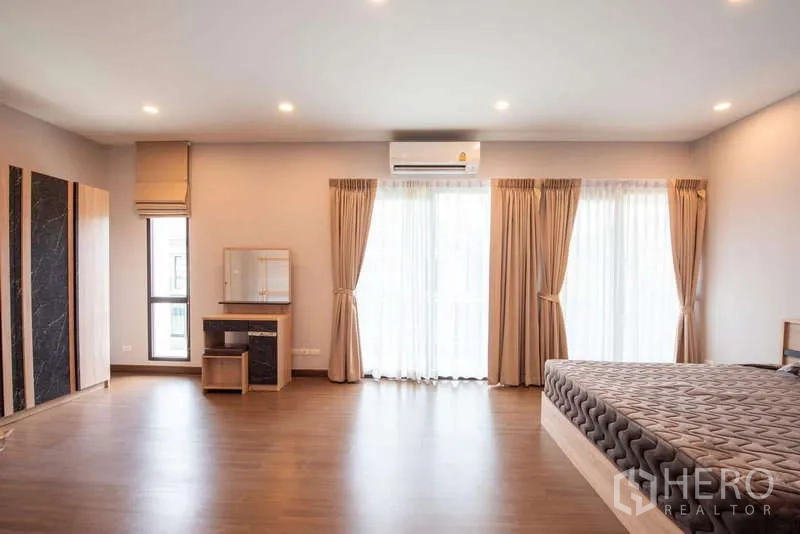 Detached House for rent or sale in Kanchanaburi - Large master bedroom with wood flooring, balcony doors, and air conditioning.