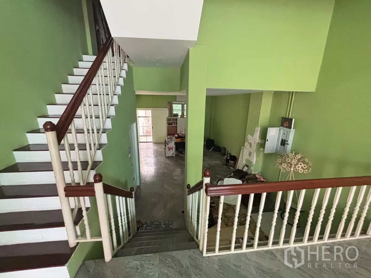 店屋 出租在Watthana, Bangkok - 从楼梯平台俯瞰开放楼层，绿色墙面与栏杆一目了然。